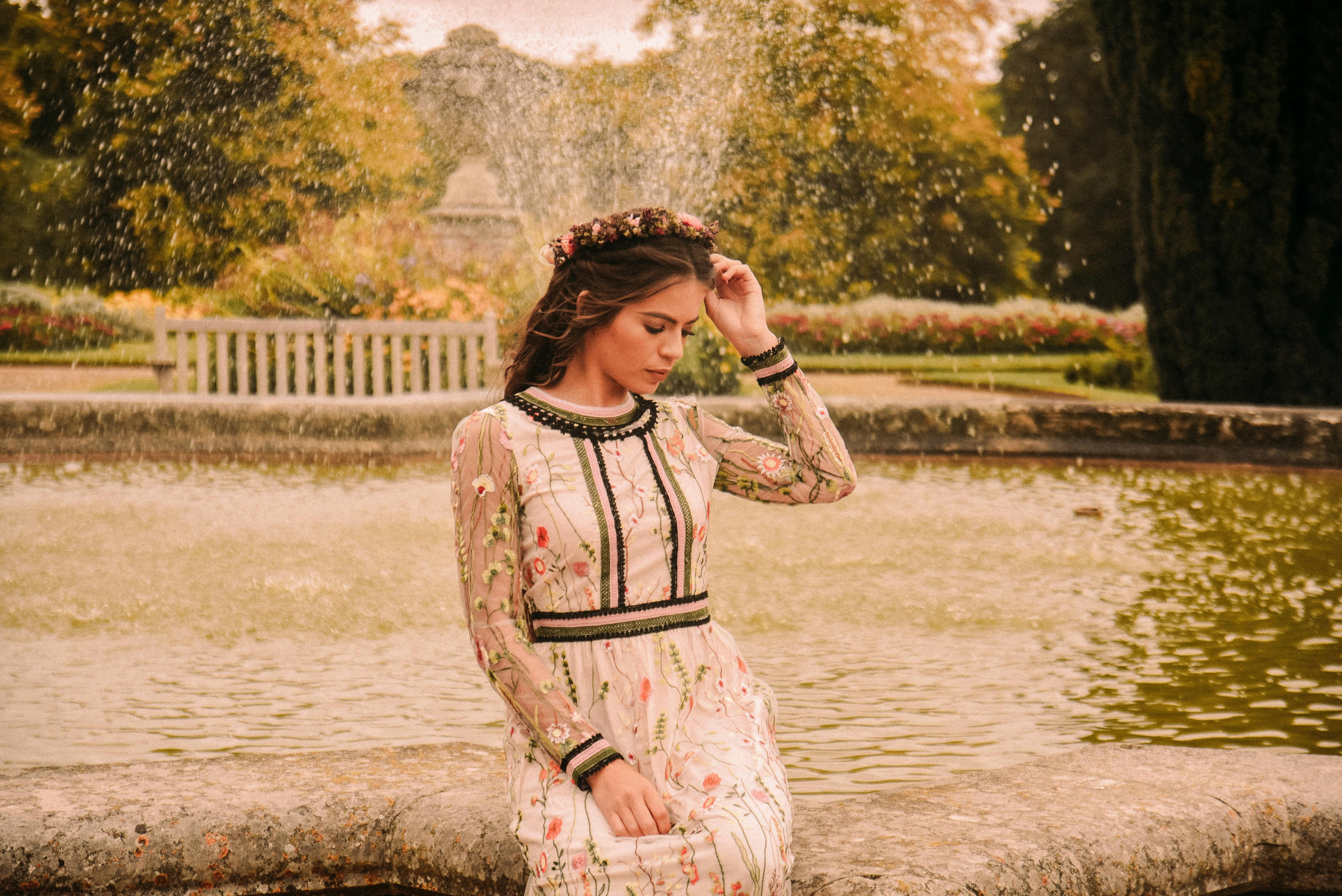 woman wearing white and black long-sleeved shirt beside water fountain outdoors